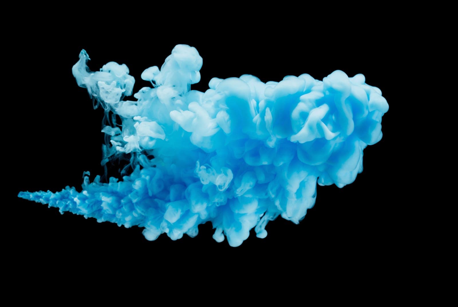 Cyan ink dispersing through black water — visual metaphor for the flow and dispersal of tissue fluids when hyaluronic acid is broken down